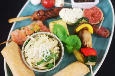 Antipasti-Teller mit Spießen, Feigen, Mozzarella und Nudelsalat